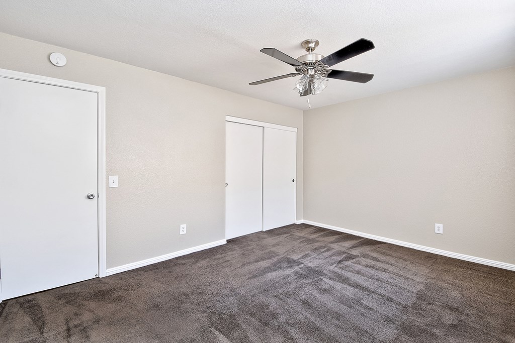 an empty living room with carpet and a ceiling fan