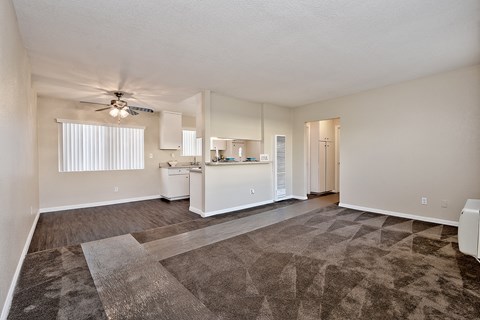 an empty living room and kitchen with a ceiling fan