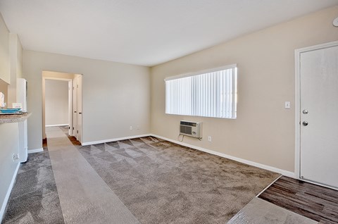 an empty living room with a window and a door to a hallway