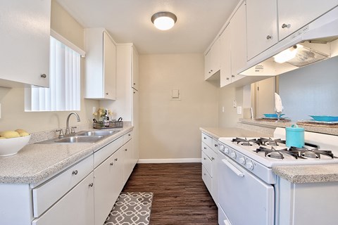 an empty kitchen with white cabinets and a stove top oven