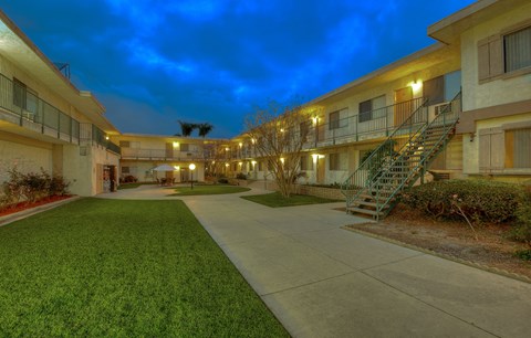 the courtyard of an apartment building at night with a staircase