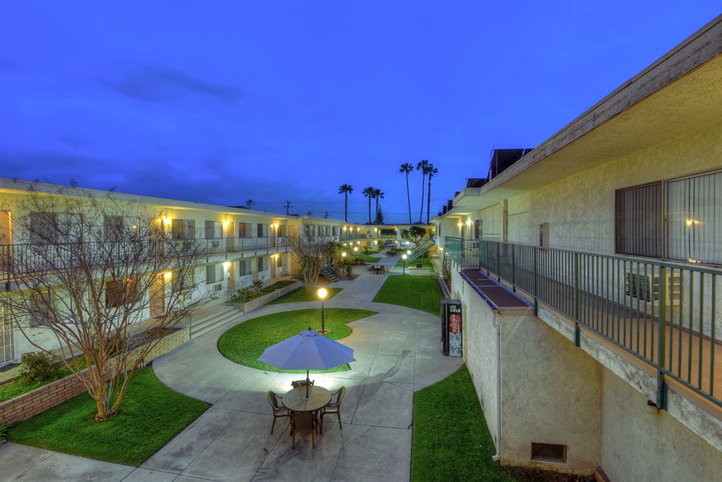 a courtyard with tables and umbrellas at night