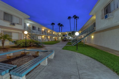 a courtyard with benches and buildings at night