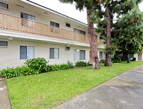 an apartment building with a lawn and trees in front of it