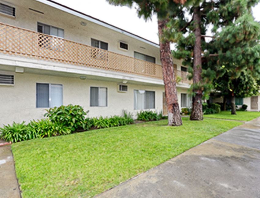 an apartment building with a lawn and trees in front of it