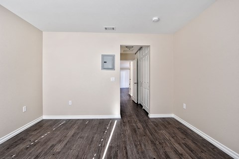 a spacious living room with white walls and wood flooring