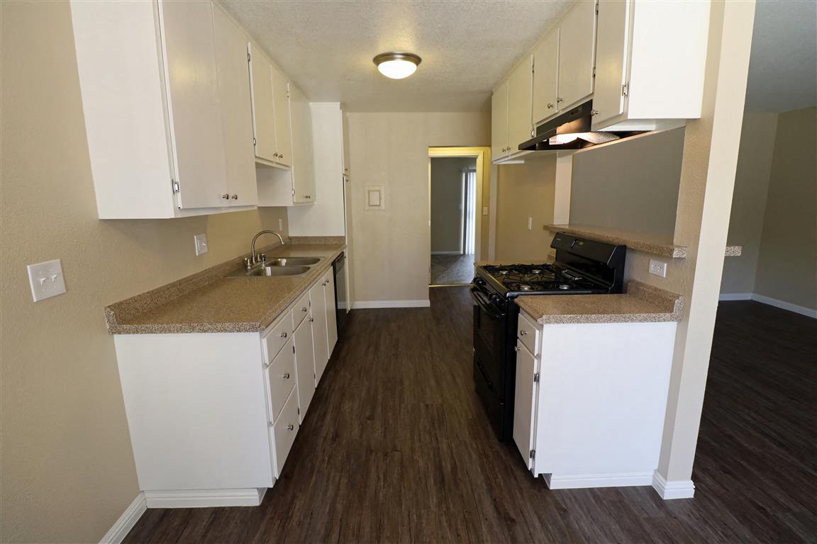 an empty kitchen with white cabinets and a black stove