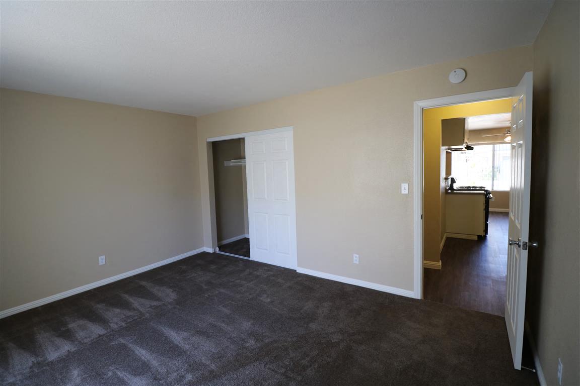 an empty living room with carpet and a door to a hallway