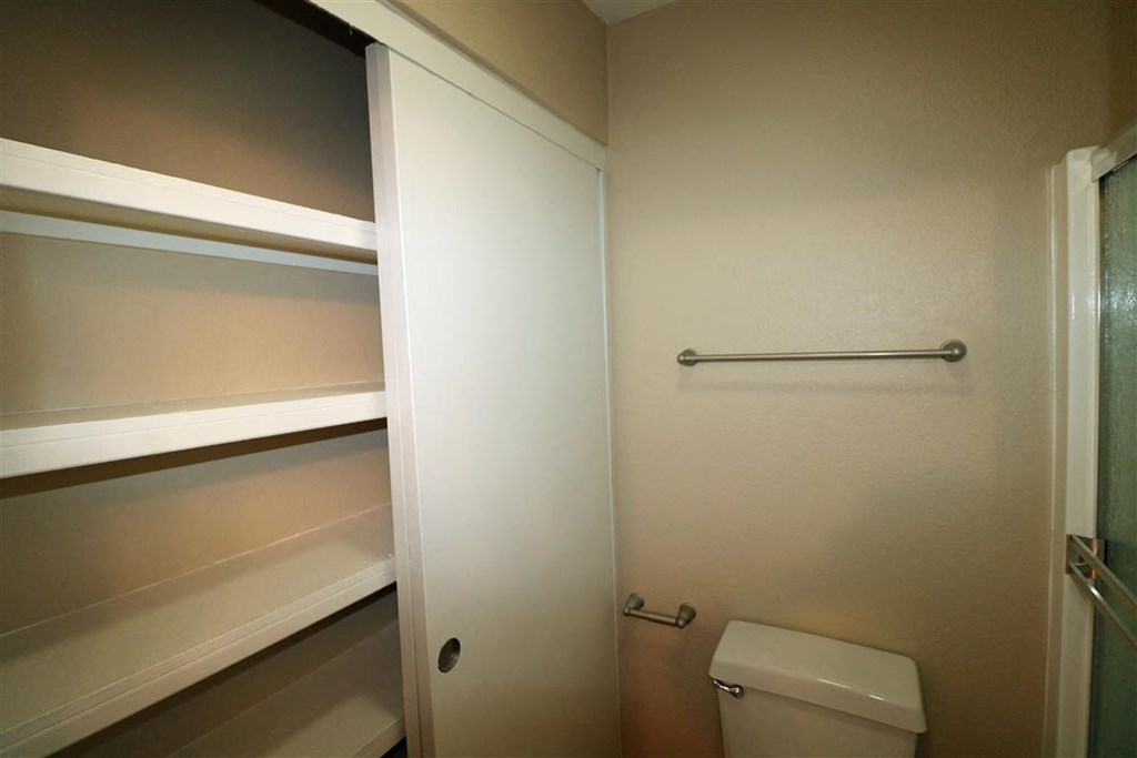 a bathroom with a toilet and a shelf above it