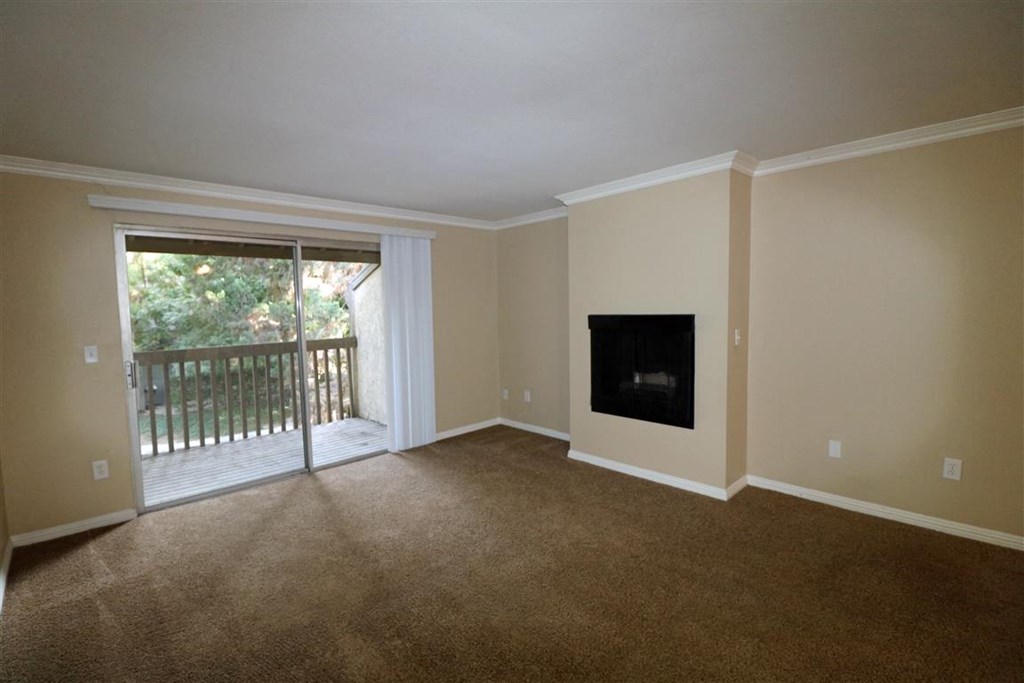 an empty living room with a fireplace and a balcony