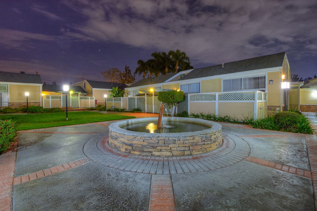 a fountain in the center of a courtyard in front of a house