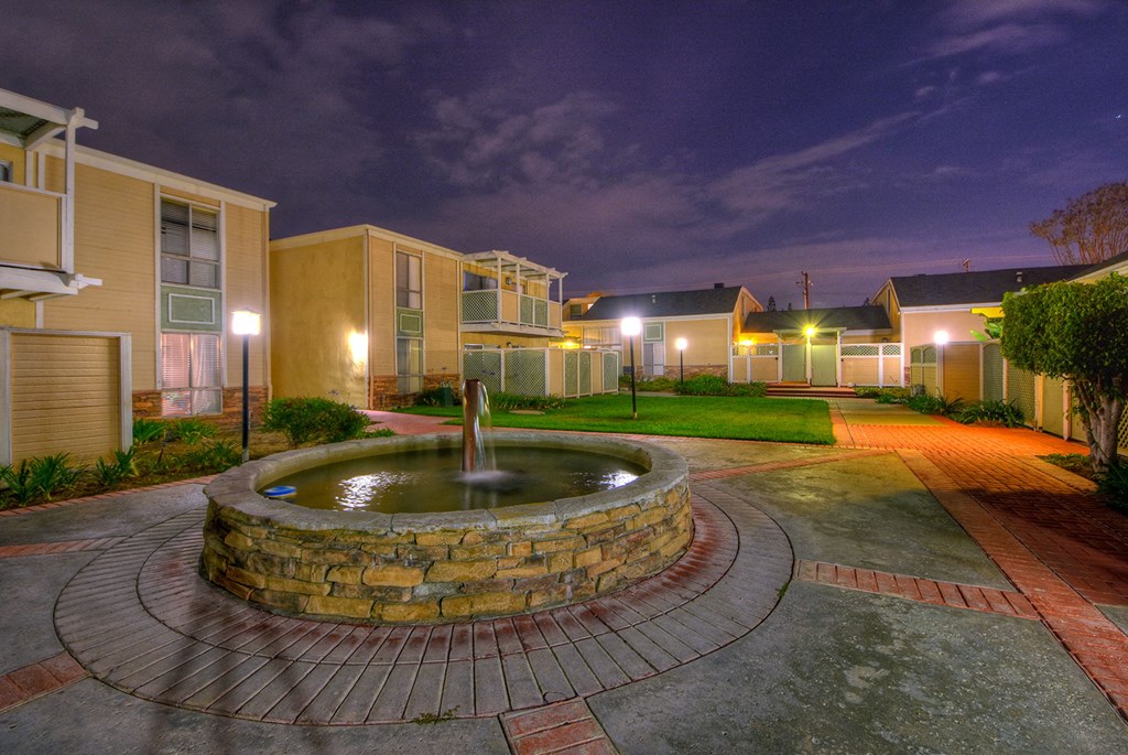 a fountain sits in the middle of a courtyard with apartments in the background