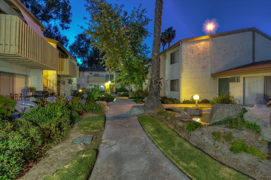a walkway between two buildings with trees and grass