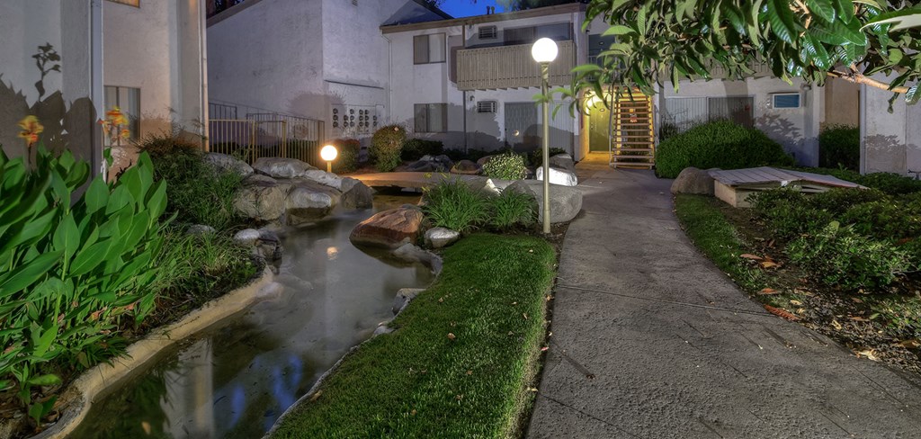a garden with a stream in front of a house