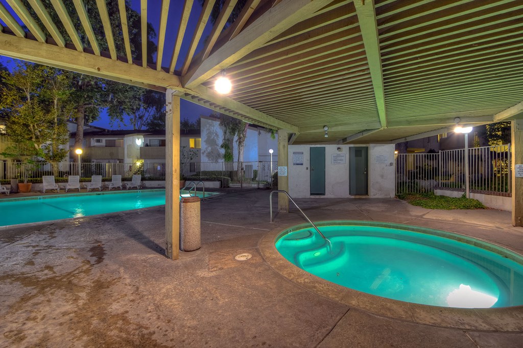 a resort style swimming pool with a hot tub at night