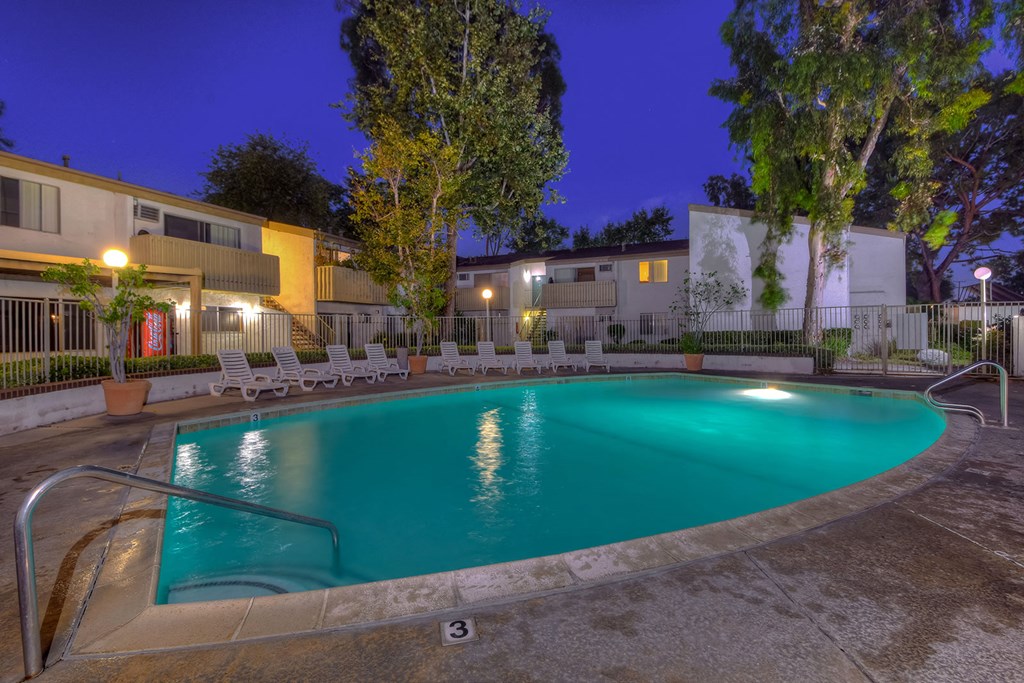 a swimming pool at night at an apartment complex
