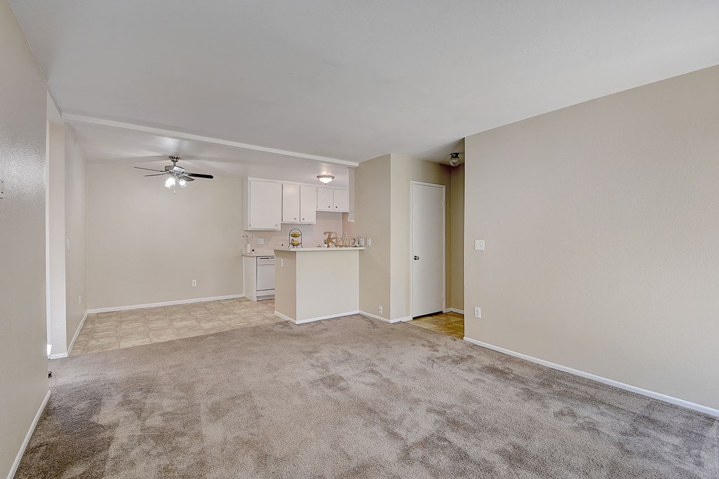 an empty living room and kitchen with a ceiling fan