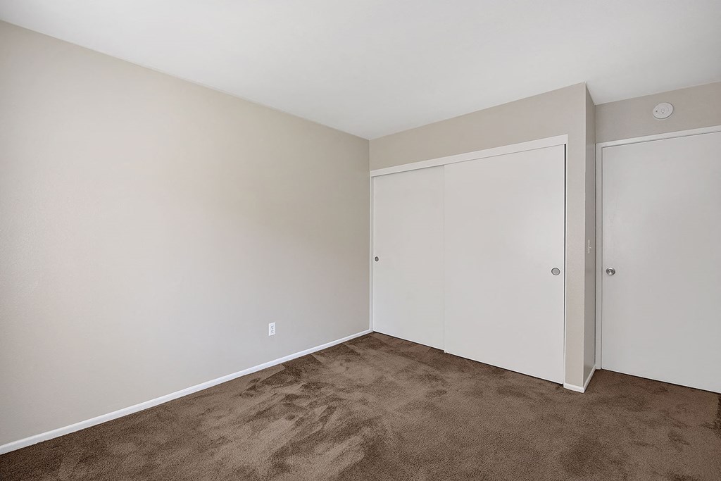 a bedroom with carpet and white walls and doors