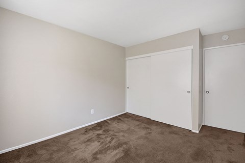 a bedroom with carpet and white walls and doors
