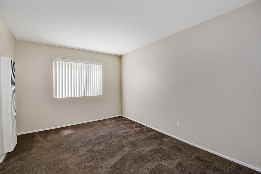 an empty room with a window and carpet