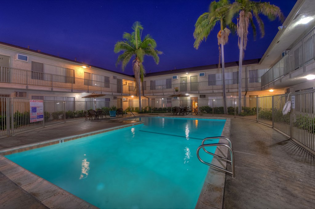 a swimming pool at night at a hotel with palm trees