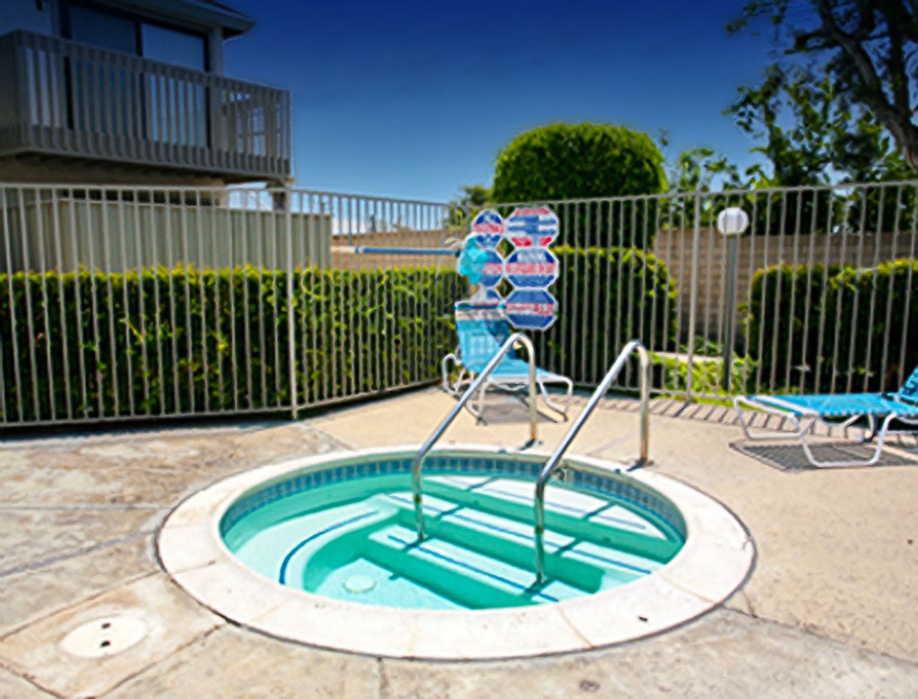 a hot tub and chairs in a pool in front of a house