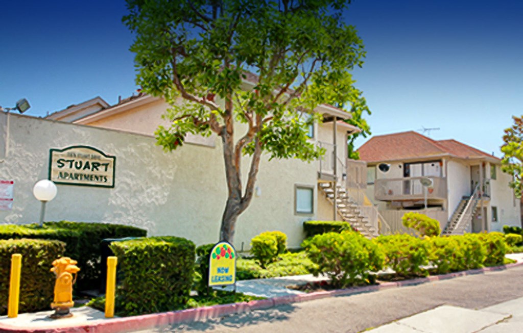 a building with a street sign and a tree in front of it