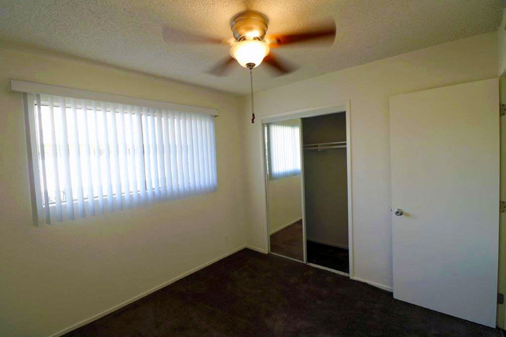 an empty living room with a ceiling fan and a closet