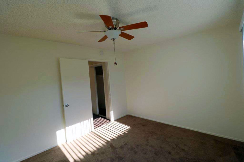 an empty living room with a ceiling fan and a window