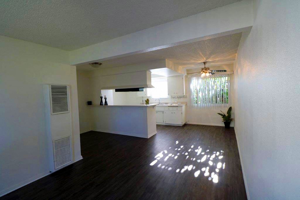 an empty living room and kitchen with a wood floor