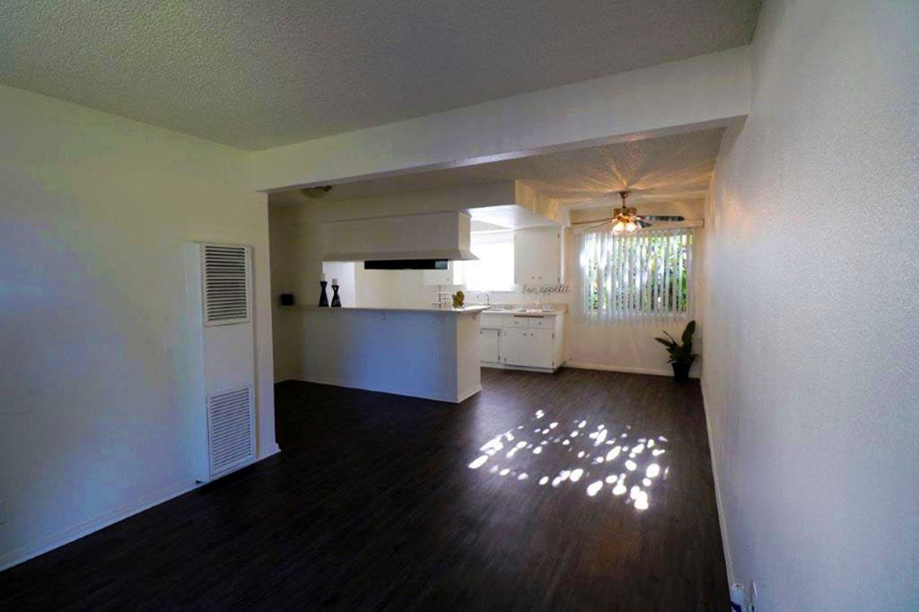 an empty living room and kitchen with a wood floor