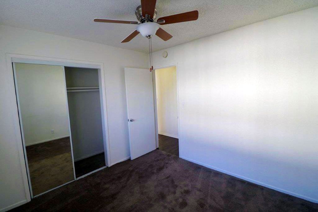 an empty room with a ceiling fan and a closet