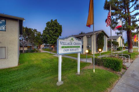 the village green neighborhood entrance sign in front of homes