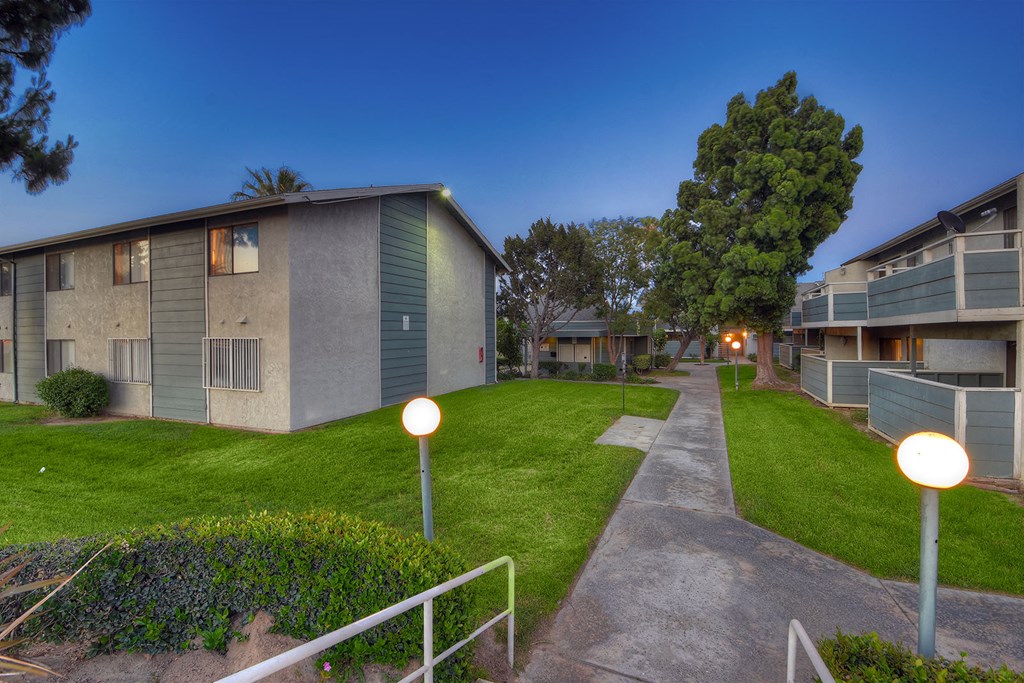 a row of apartment buildings with grass and trees