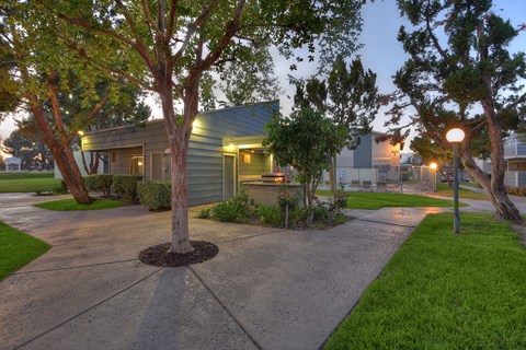 a sidewalk leading to a green house with trees