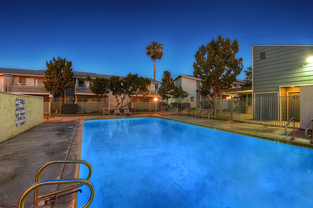 a swimming pool at night at an apartment complex with a blue pool