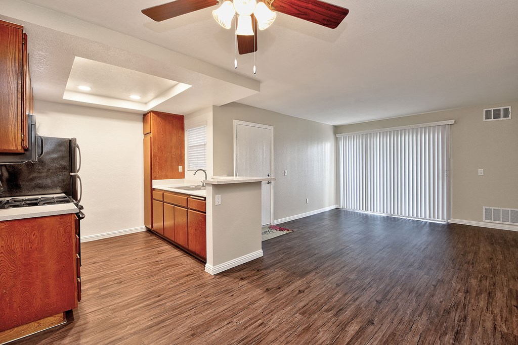 an empty kitchen and living room with wood flooring and a ceiling fan