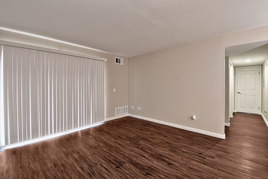 an empty living room with wood flooring and a white door