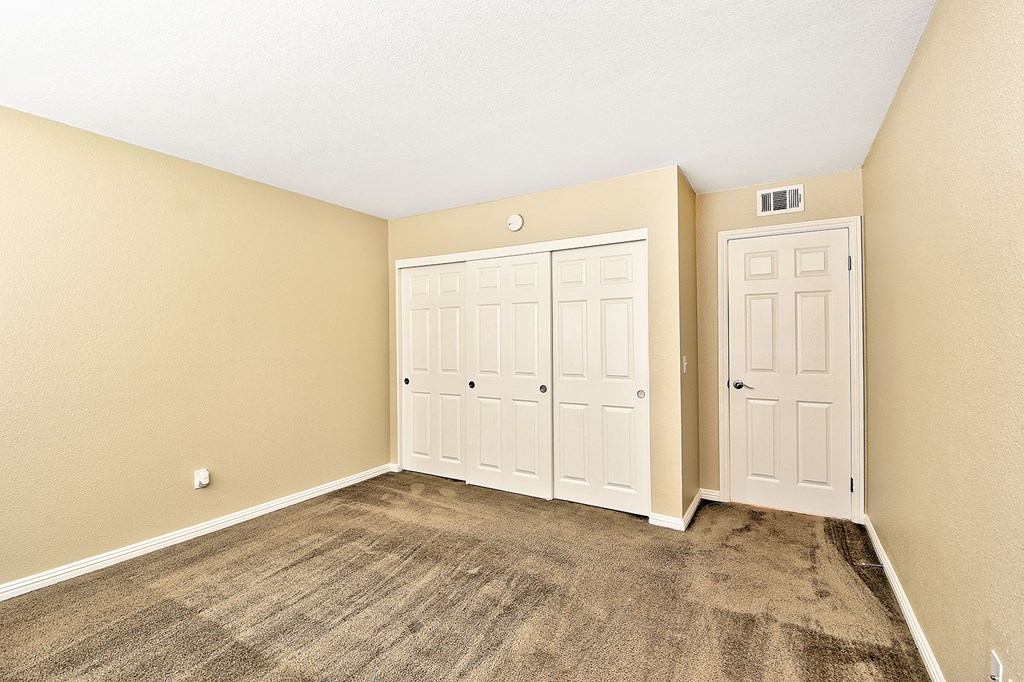 an empty room with two doors and a carpeted floor