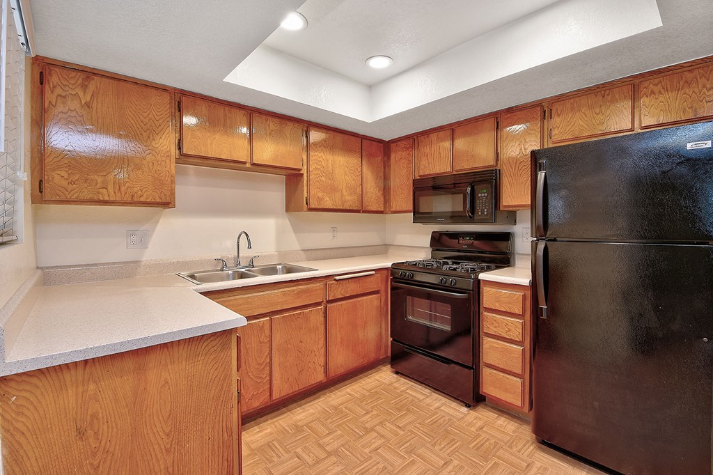 a kitchen with wooden cabinets and a black refrigerator
