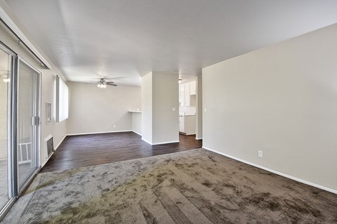 a spacious living room with hard wood floors and a ceiling fan