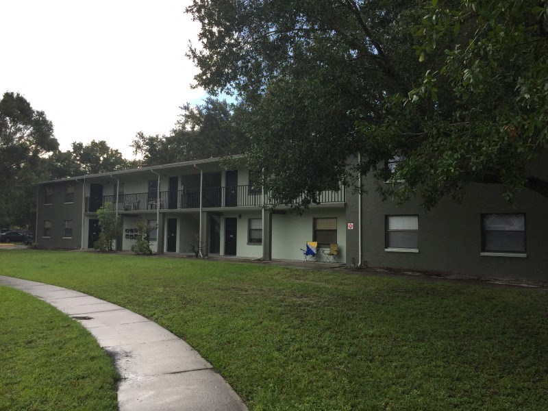 an apartment building with a green lawn and a sidewalk