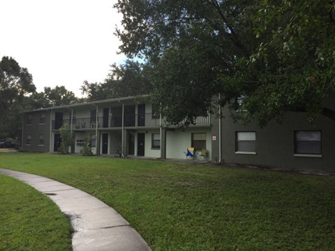 an apartment building with a green lawn and a sidewalk
