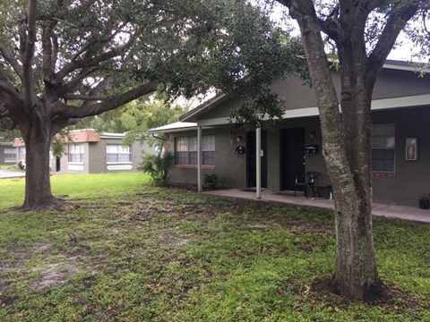 a house with a yard and trees in front of it