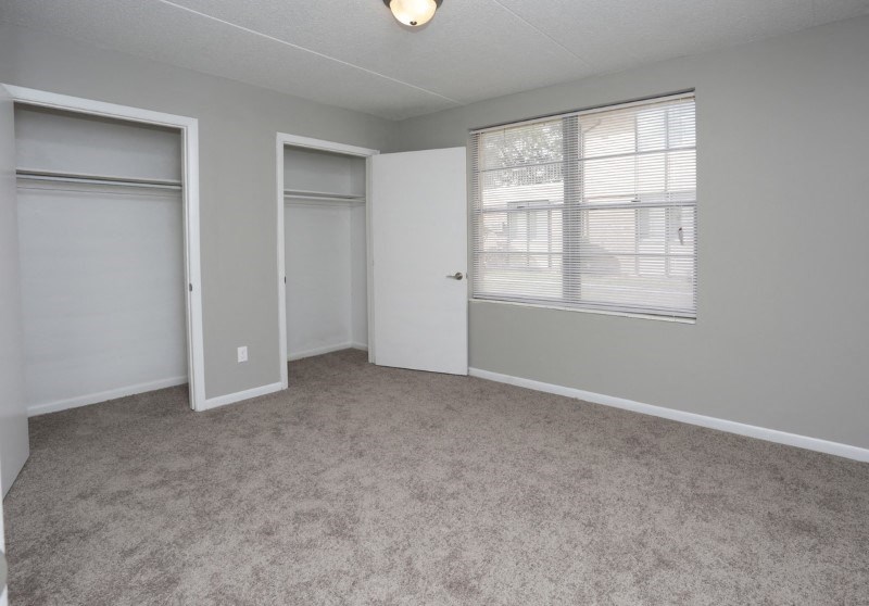 an empty room with a window and two closets
