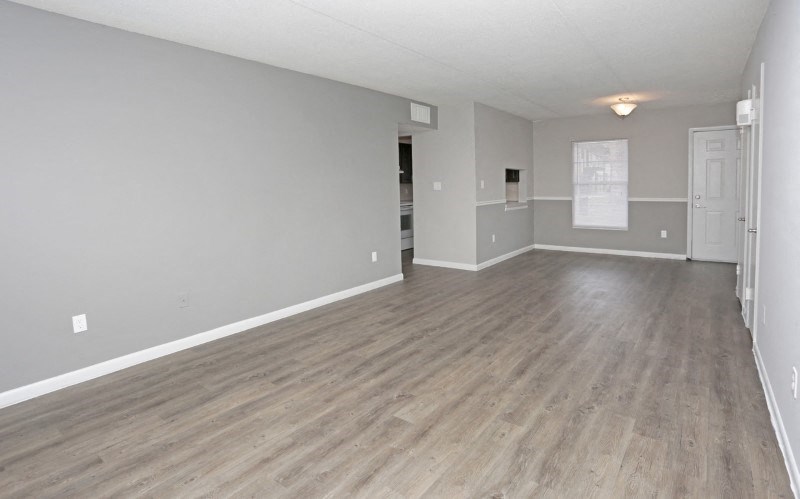 an empty living room with a hard wood floor and white walls