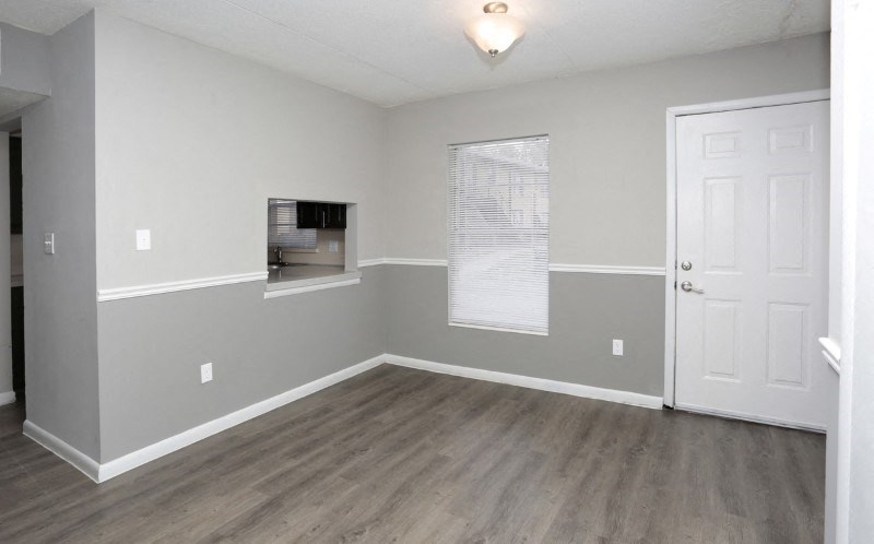 an empty living room with a white door and a window