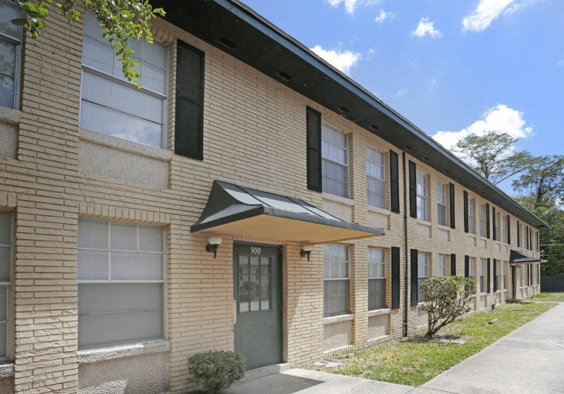 a brick apartment building with a sidewalk in front of it
