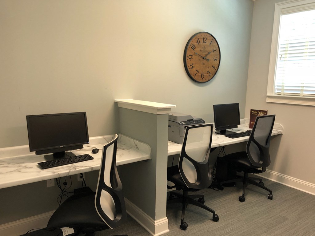 an office with three desks with computers and a clock on the wall