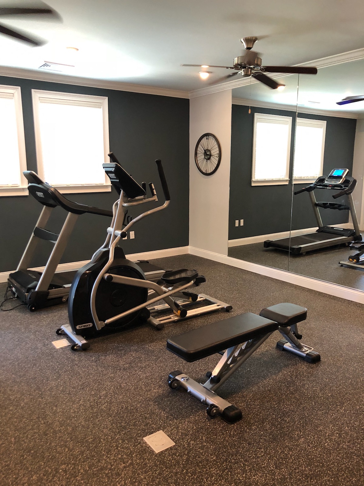 a home gym with exercise equipment and a ceiling fan
